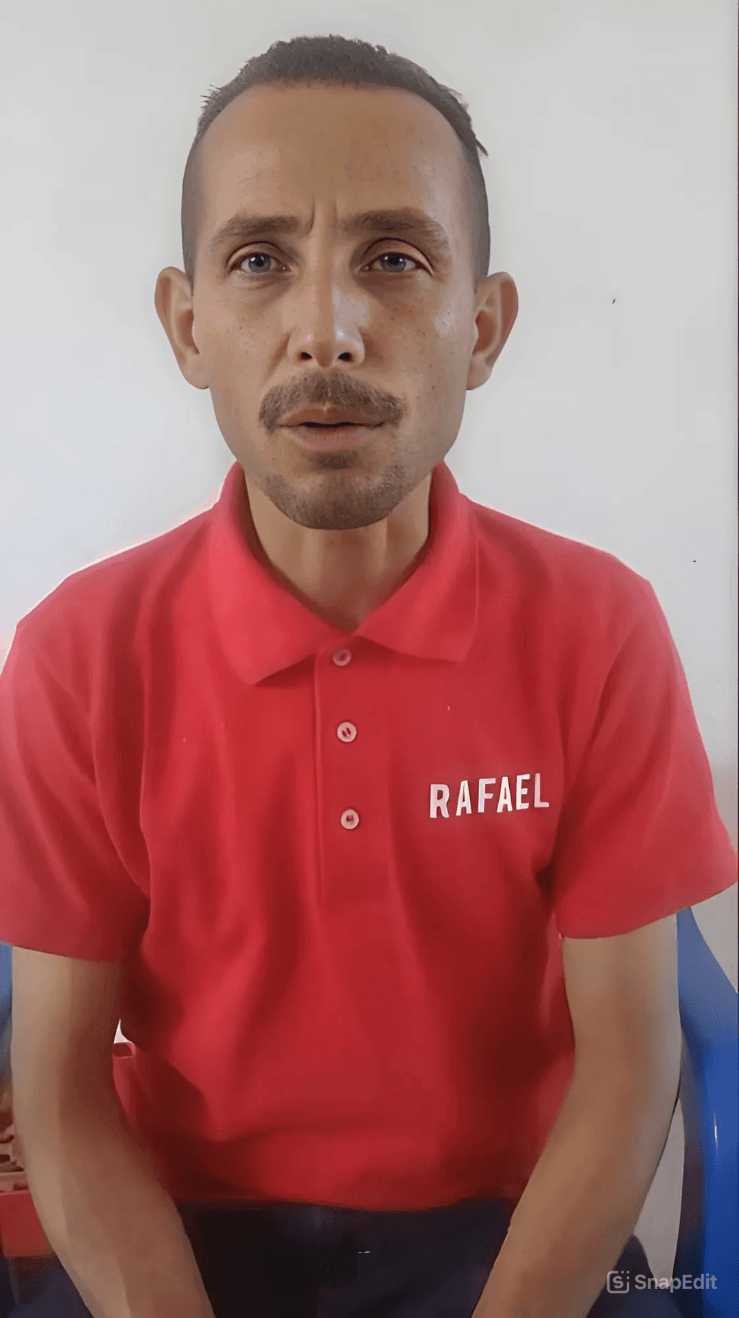 Person wearing a red polo shirt with 'Rafael' embroidered, sitting against a plain background.