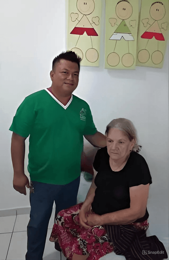 Man in green shirt standing beside seated woman in black, colorful drawings on wall behind them.