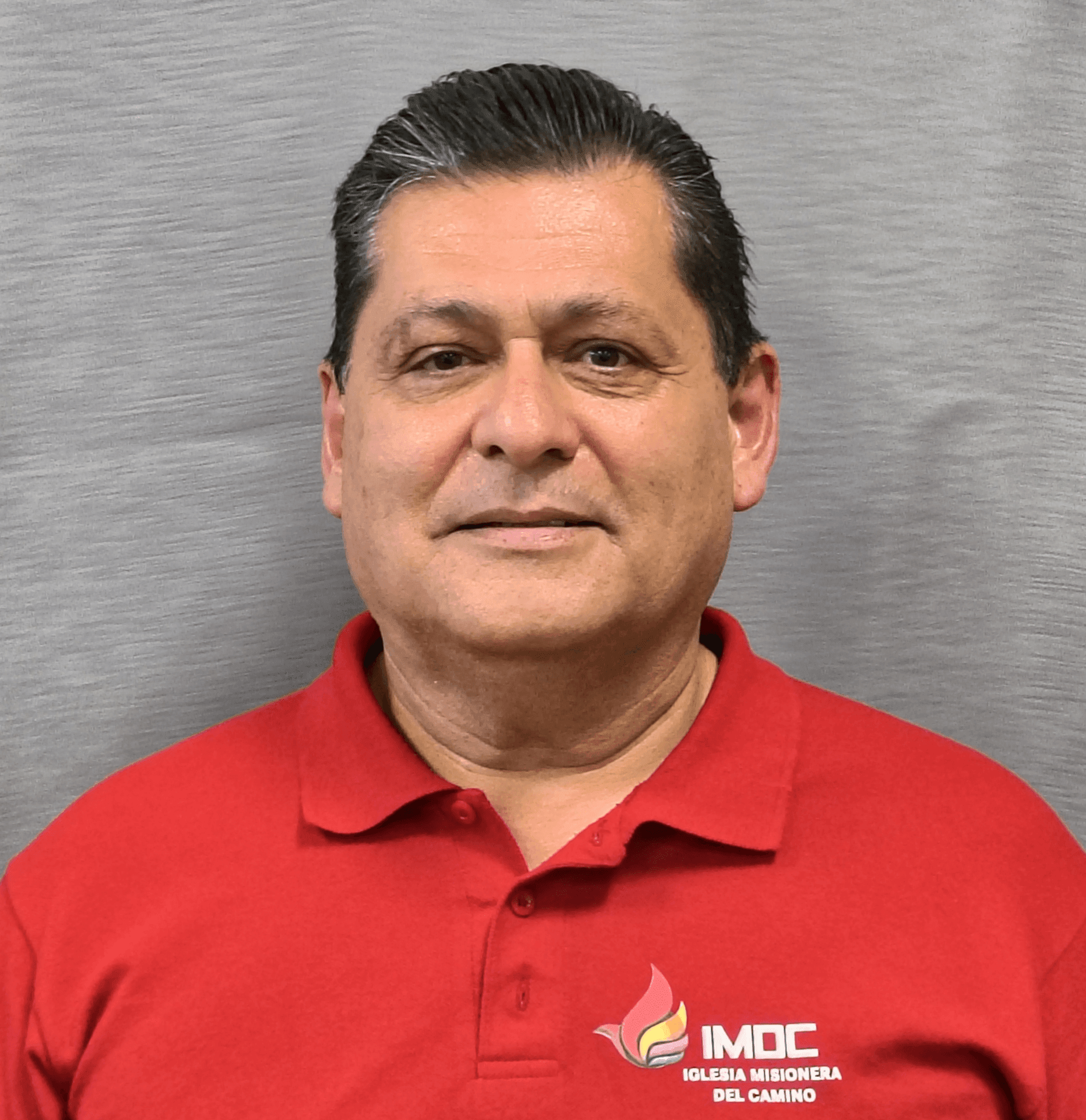 Man in a red polo shirt with IMDC logo on a gray background.